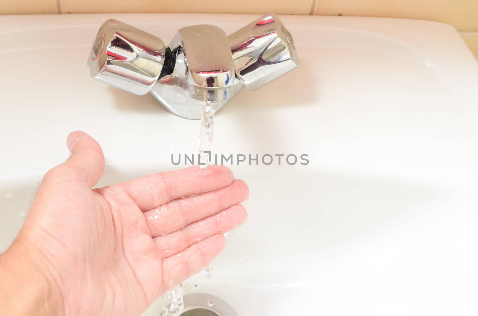 human hand being touched under stream of pure water from tap