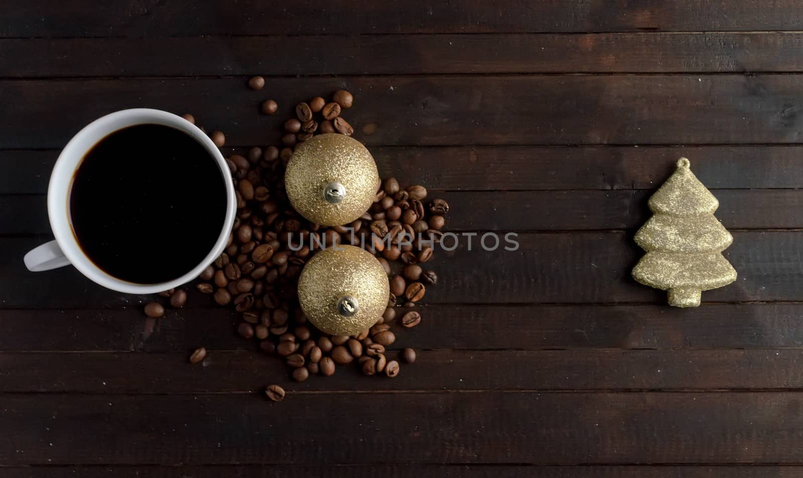 Cup of coffee with coffee beans ,two pair Christmas golden balls and toy Christmas tree on wooden background.Christmas and new year concept.Copyspace.