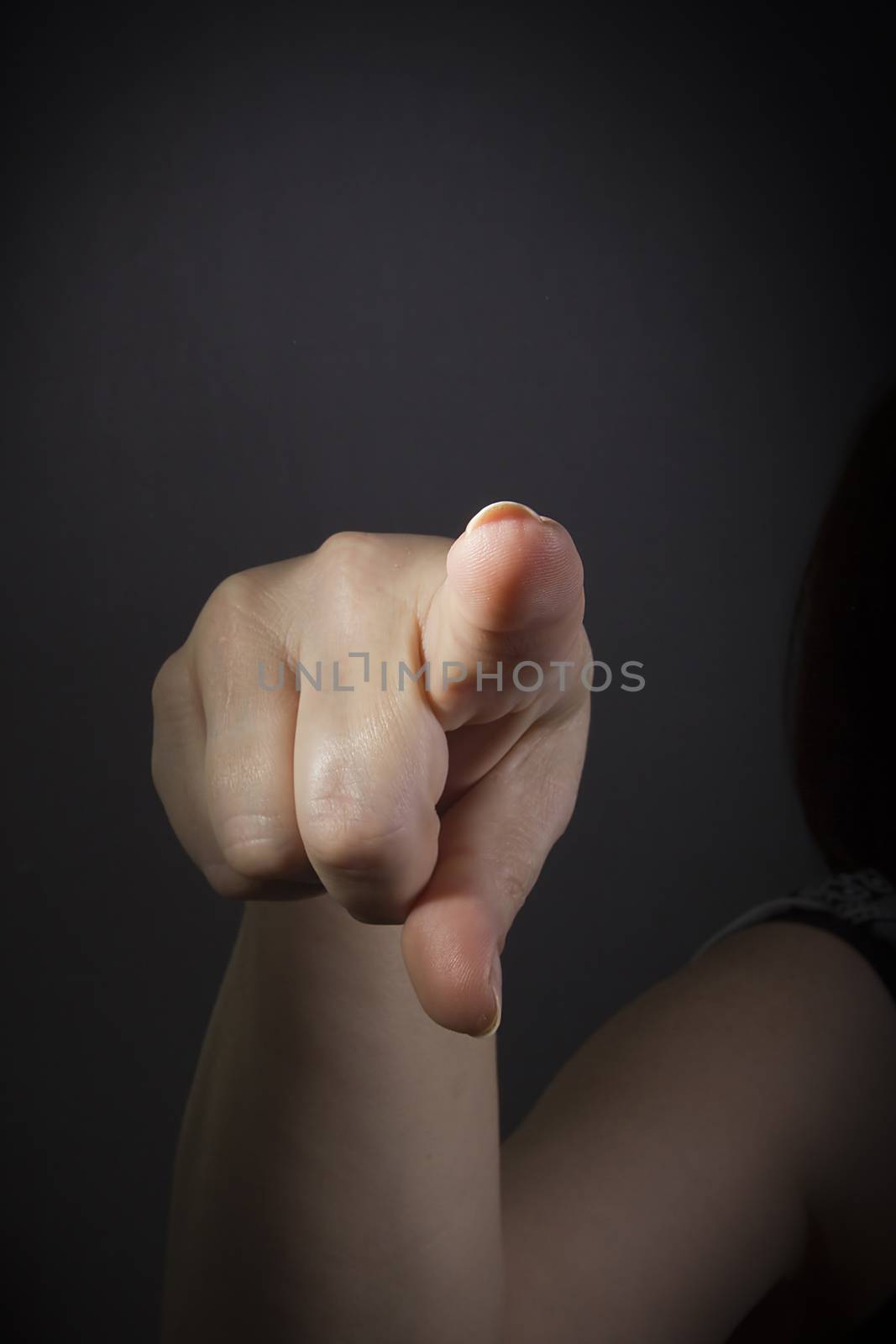 Female finger pointing at you closeup on black background