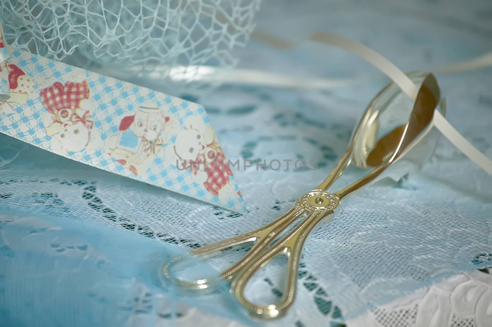 Silver pliers dipped in blue decorations used to collect and donate the colored candies used as favors for a Catholic baptism.