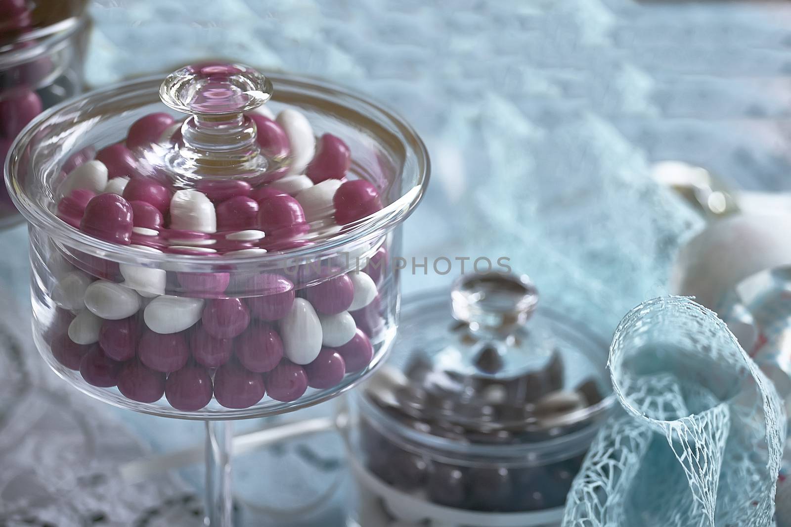 Glass container for colored candies used as a wedding favor and decoration for catholic baptism.