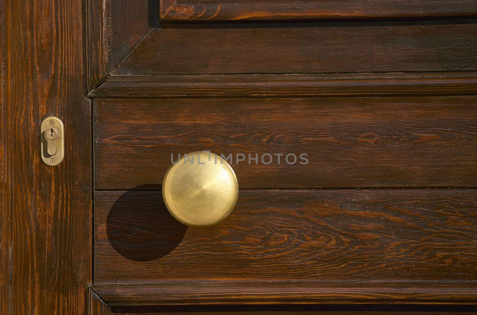 Detail of the handle and lock of a handcrafted dark wooden house door.