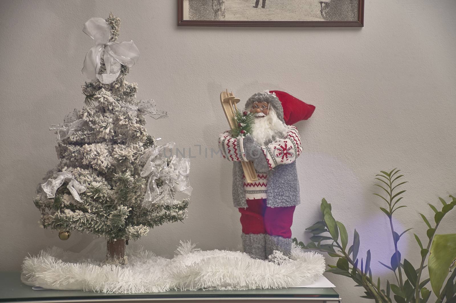 Set of Christmas decorations of interiors composed of a statue of Santa Claus and a fake Christmas tree resting on a piece of furniture.