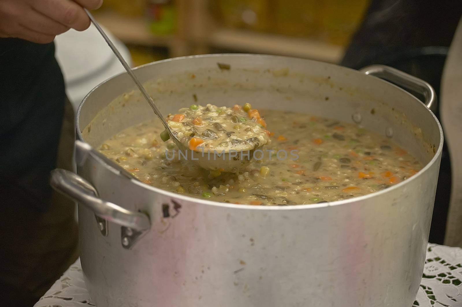 Large pot full of vegetable and cereal soup ready to be served to diners.
