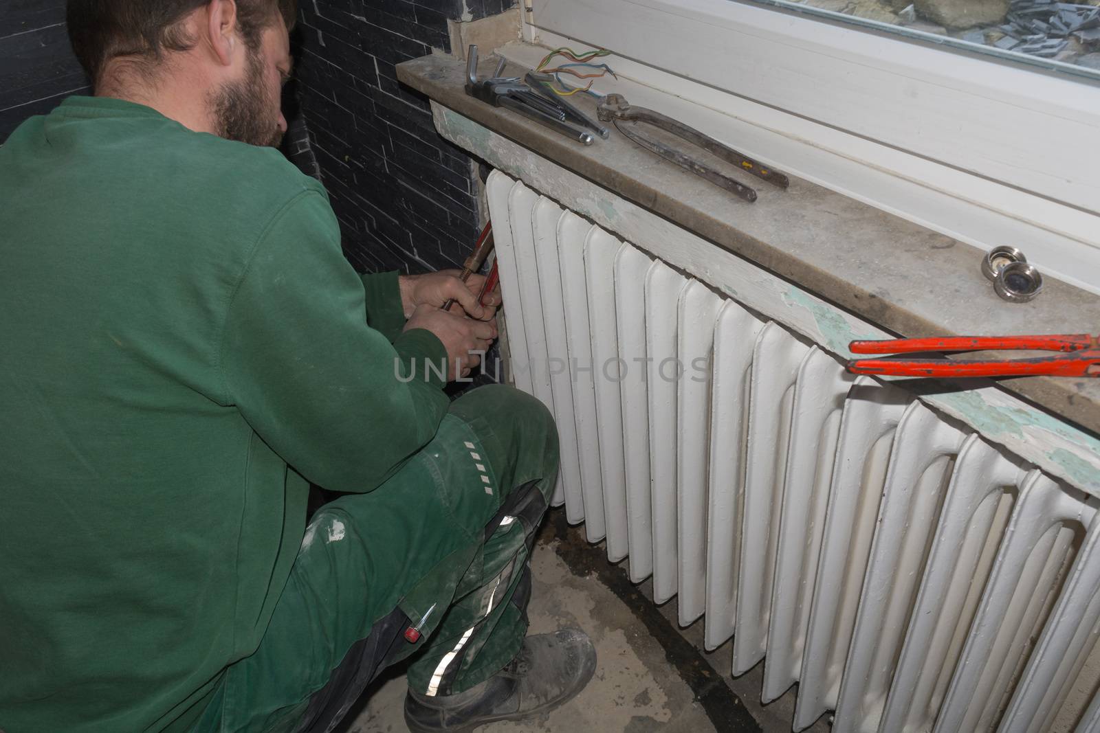 Plumbing or heating plumber dismantles an old finned tube radiator