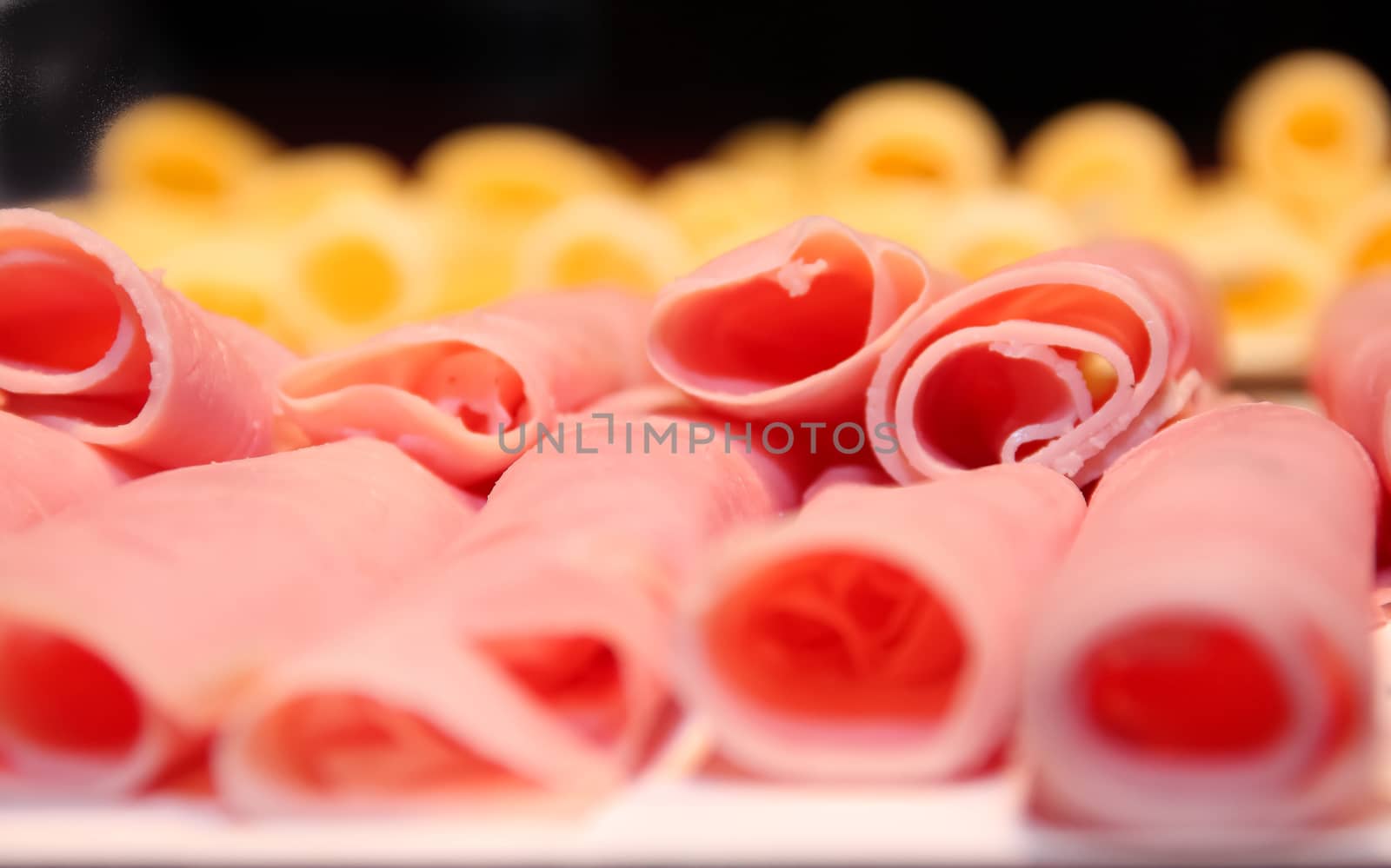 detail of ham in rolls with cheese out of focus in the background
