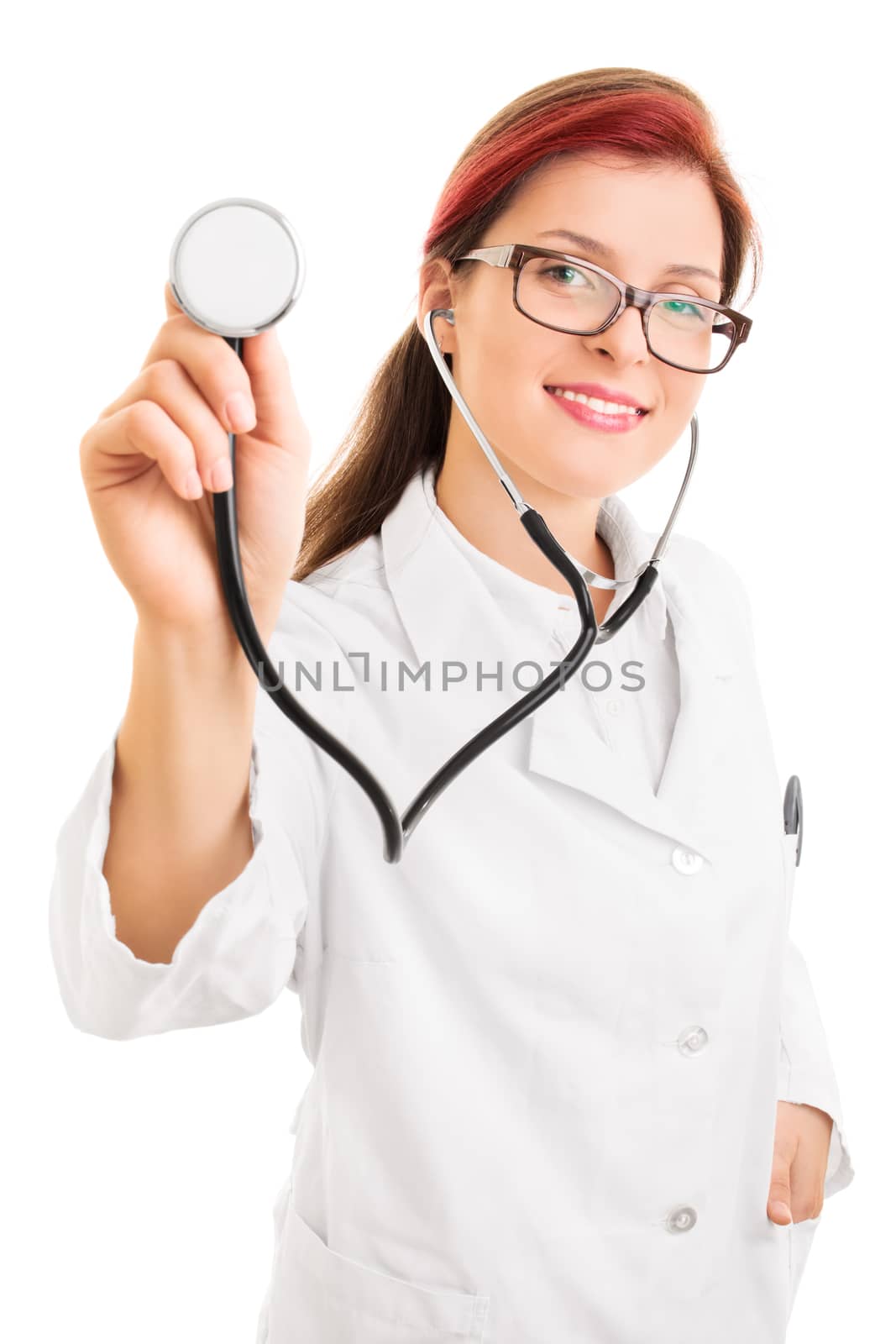 Portrait of a smiling young female health care professional or doctor or nurse with glasses holding stethoscope pointed toward camera, isolated on white background. Listening to your heart.