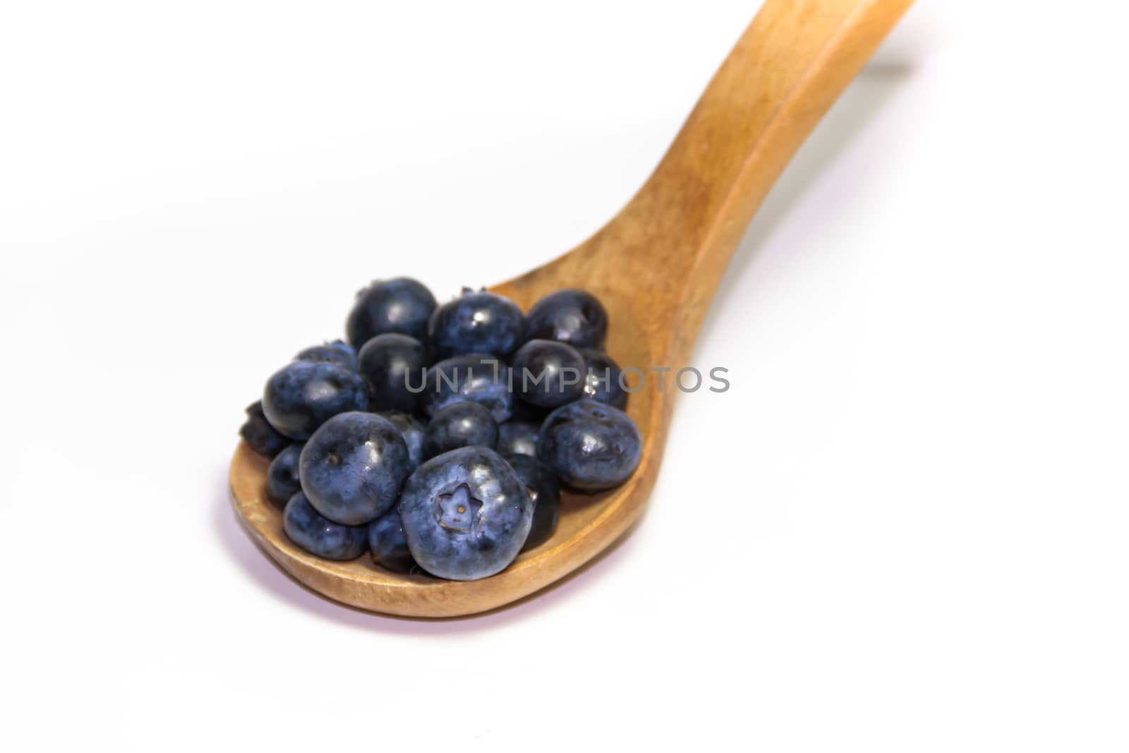 red fruits on white background and wooden spoon