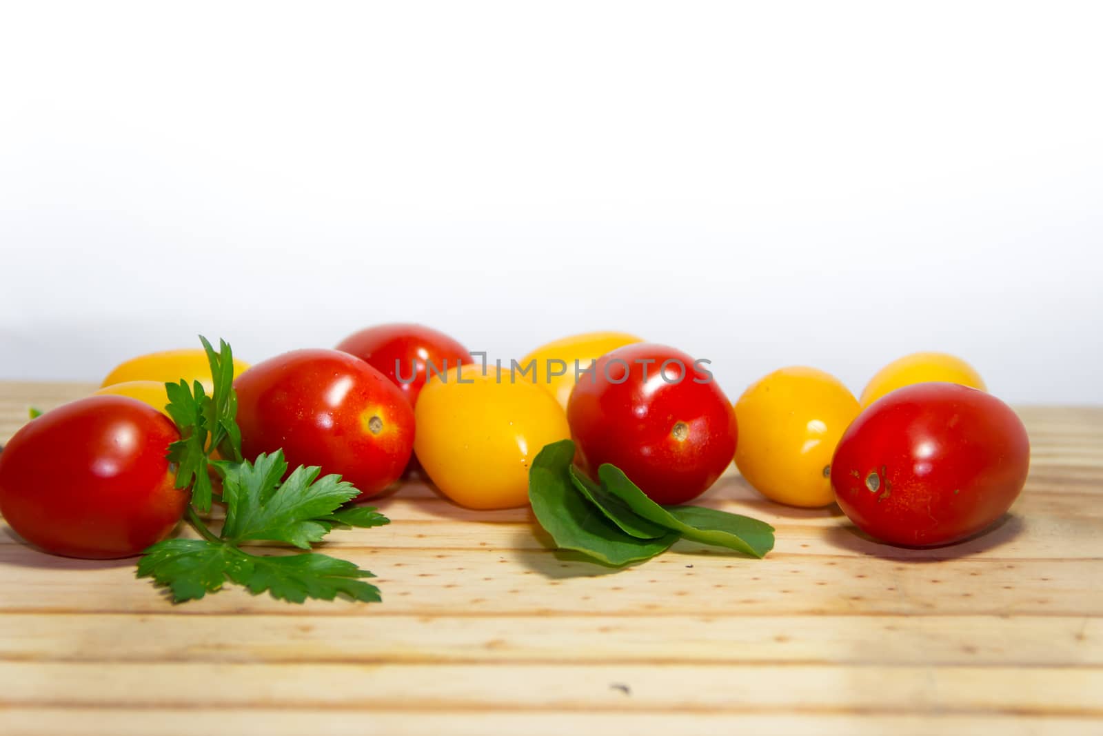 red and yellow cherry tomatoes on wooden background by GabrielaBertolini