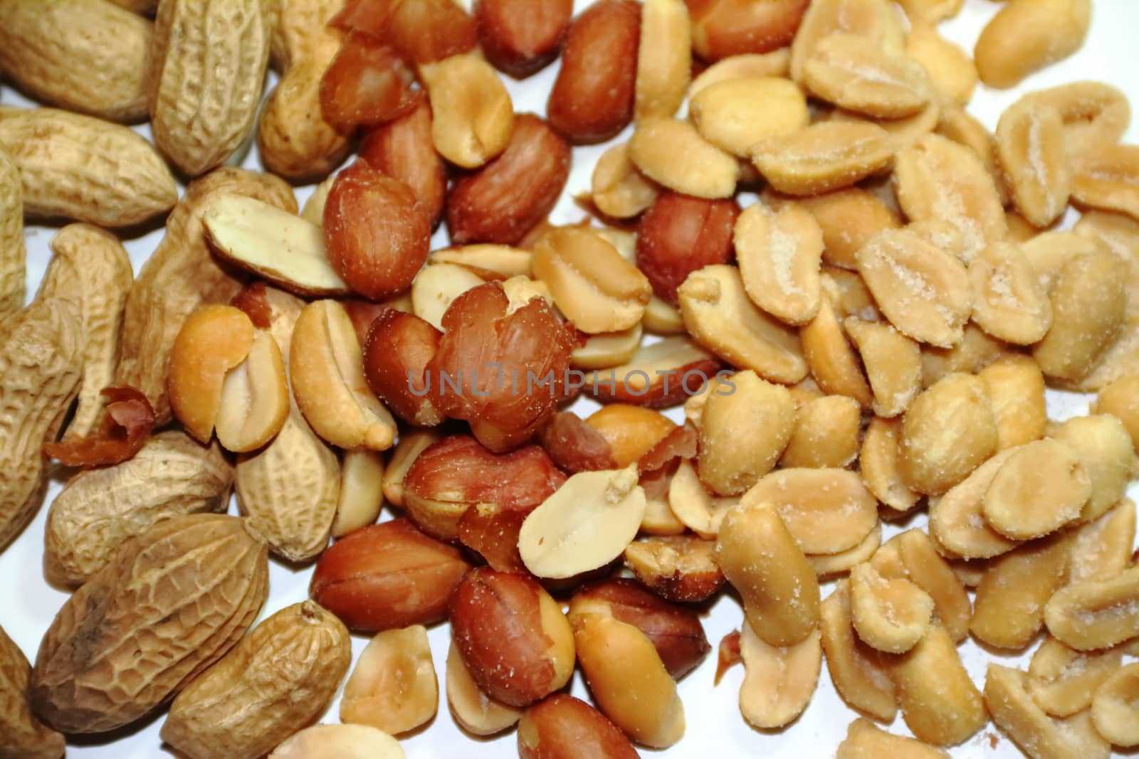 variety of salty peanuts with and without peel on white background