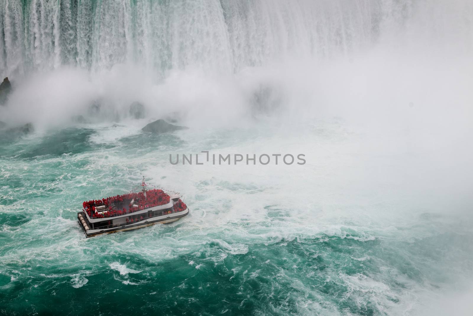 View of Niagara Falls by day from the Canadian side with turistic boat tour. Famous international destination it have been seen.