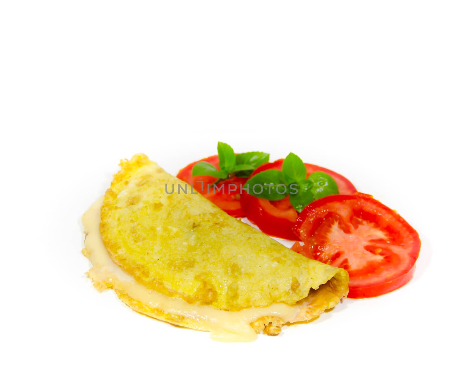 omelette made with beaten eggs stuffed with onion cheese and tomatoes on white background with sliced tomatoes and basil
