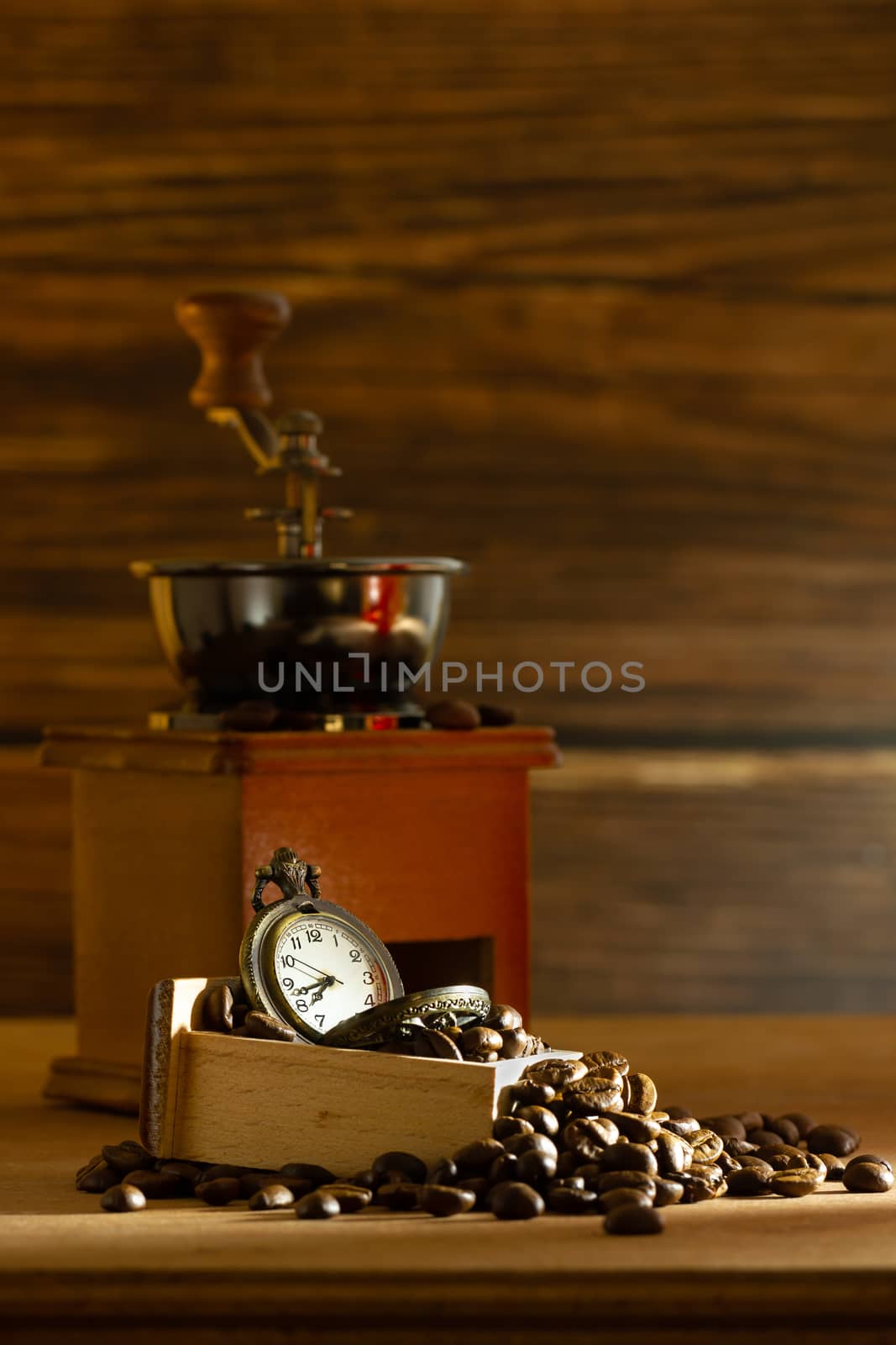 Coffee bean and pocket watch. Manual grinder on table in morning. Concept of coffee time.