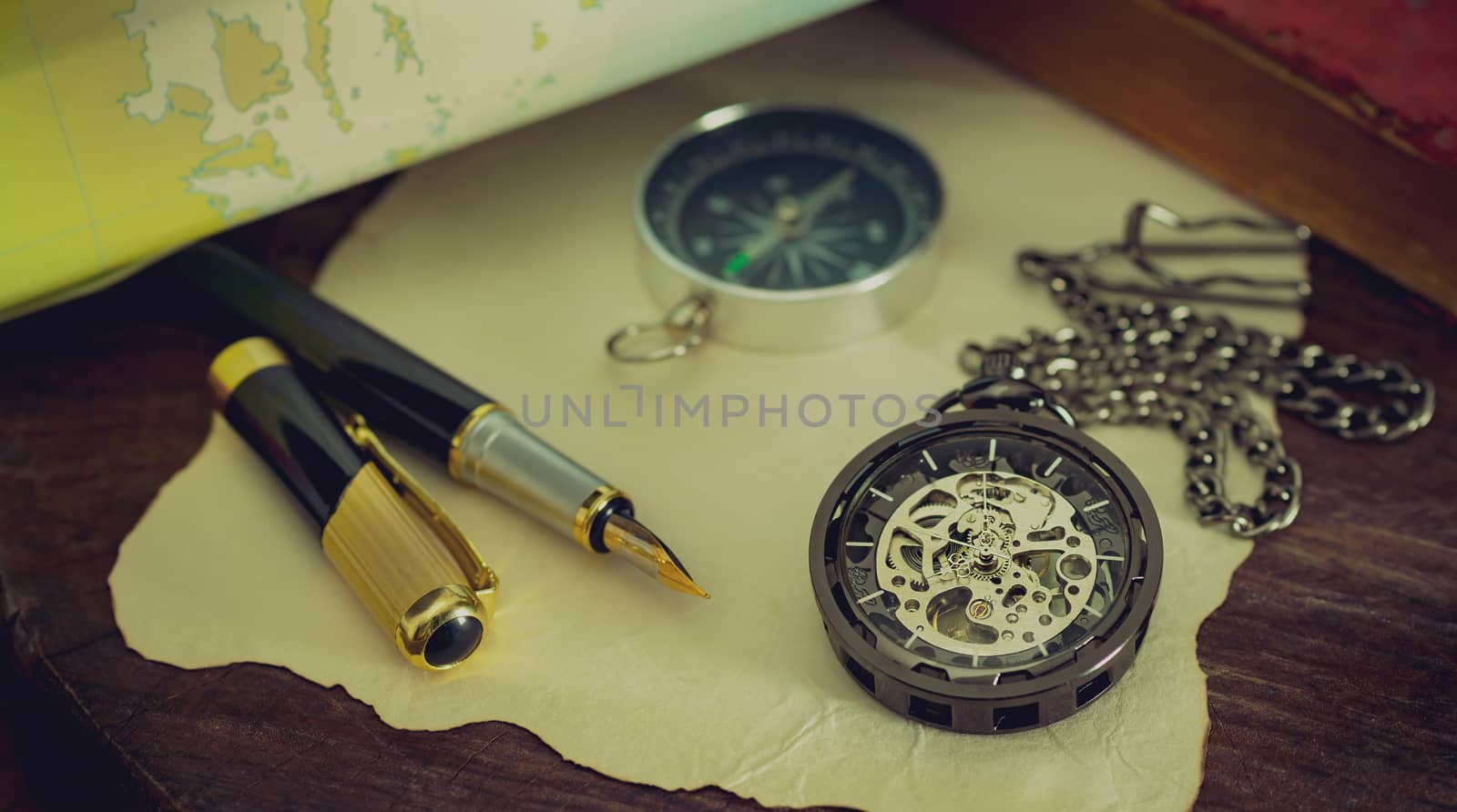 Pocket watch with old books and pen with paper map on the table  by SaitanSainam