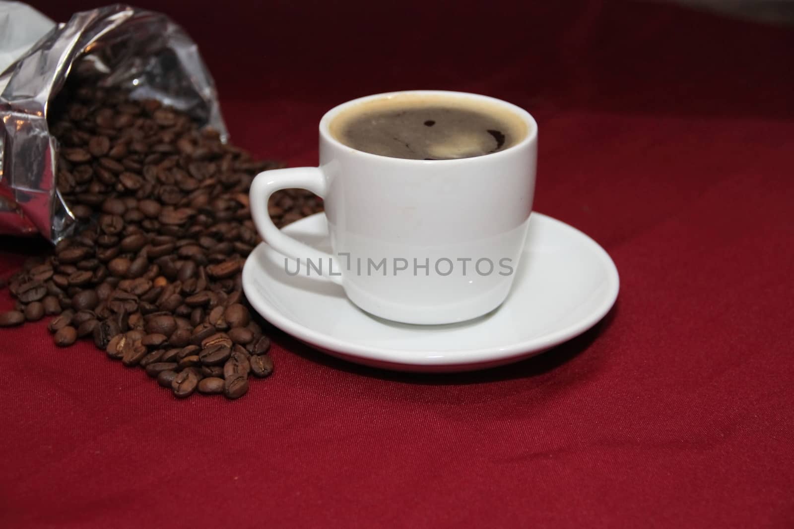 white cup of coffee with beans on background board