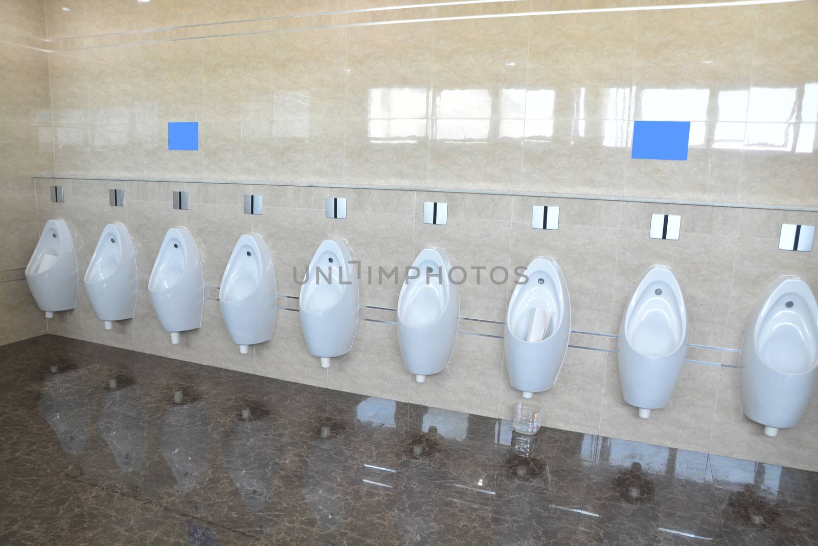Row of urinal toilet blocks for man tiled wall in public toilet