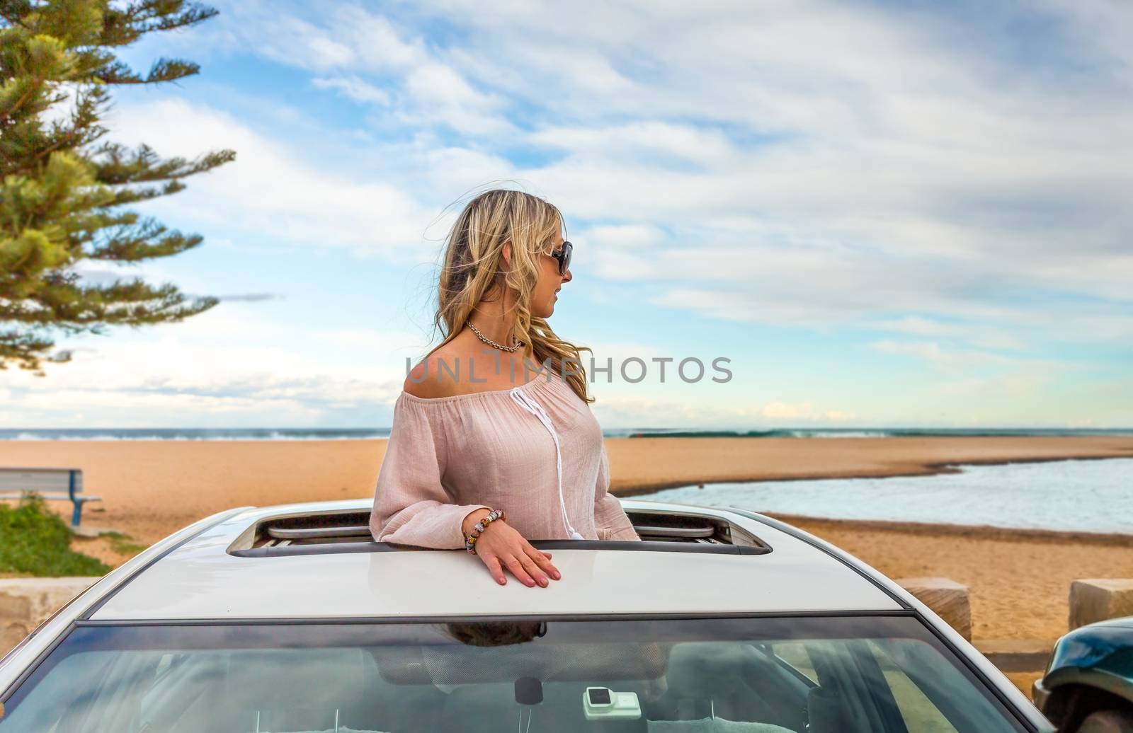 Road trip summer beach vibes.  Carefree woman in sunroof car by by lovleah