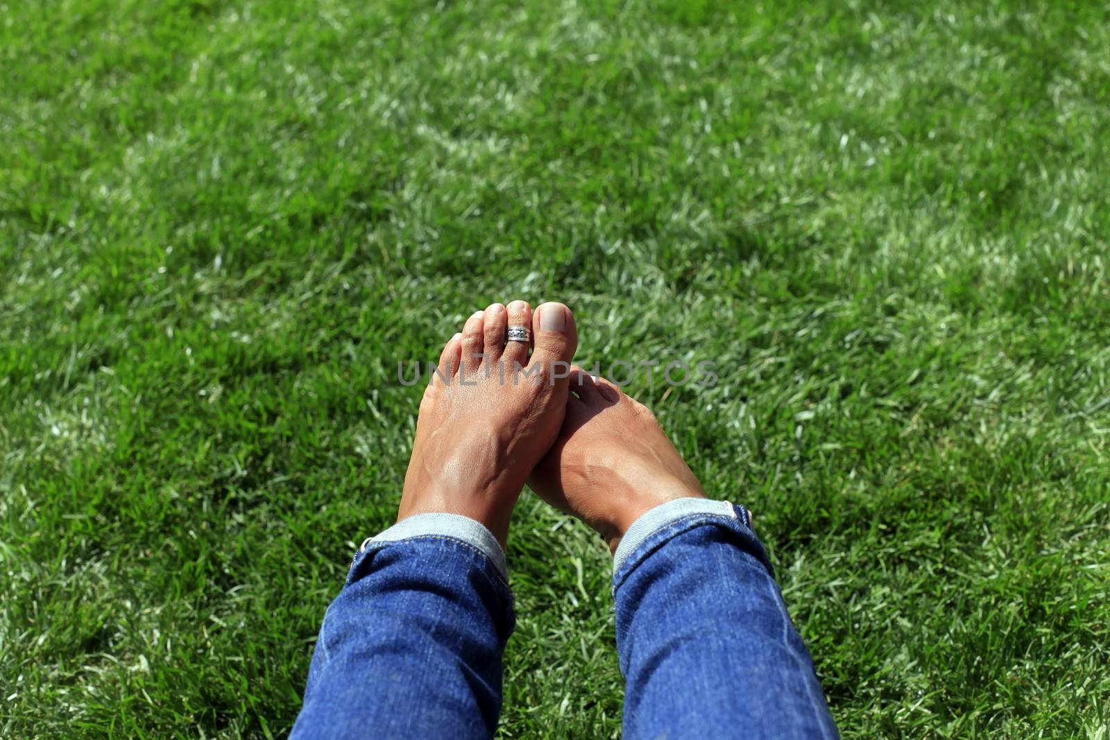 Bare feet in green grass, woman relaxing in nature