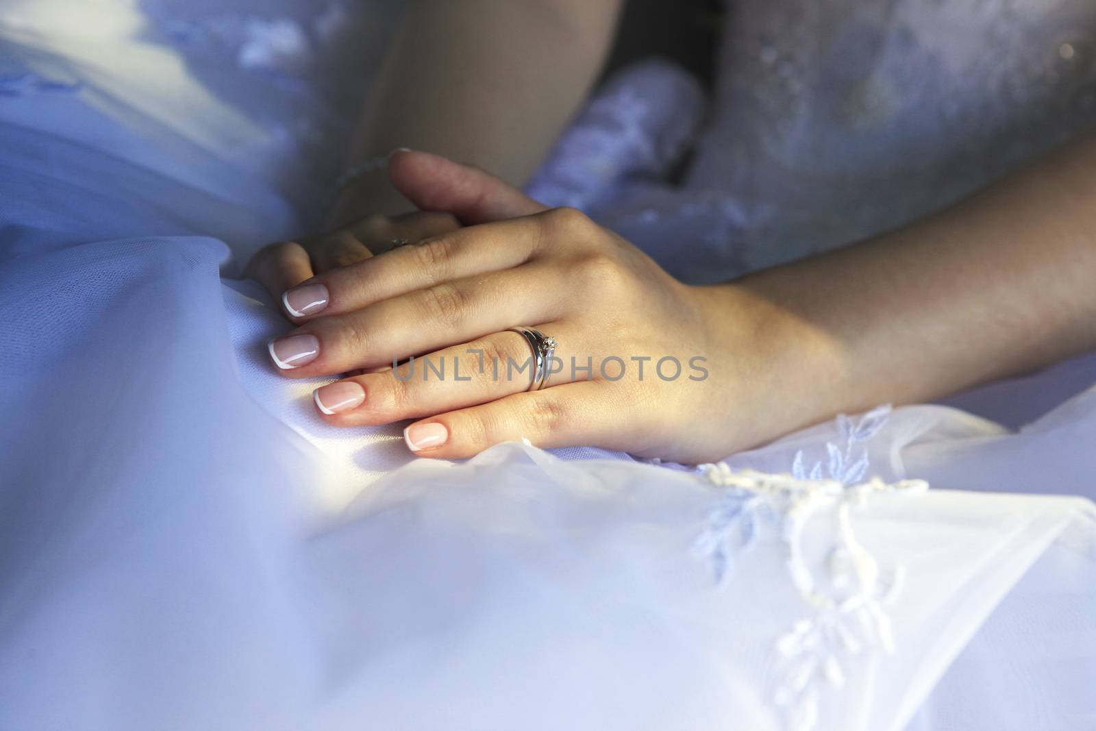 Hands of the bride on a background of a wedding dress by friday