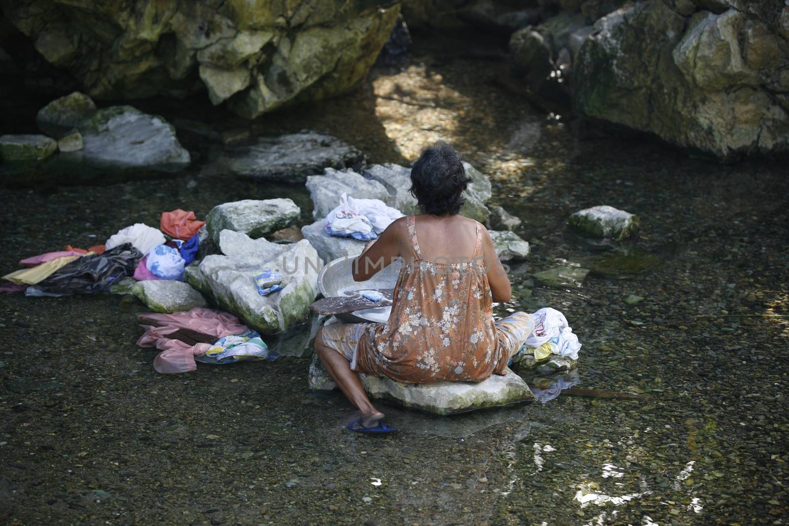 Filipino elderly woman washing clothes in the river. Philippines by friday