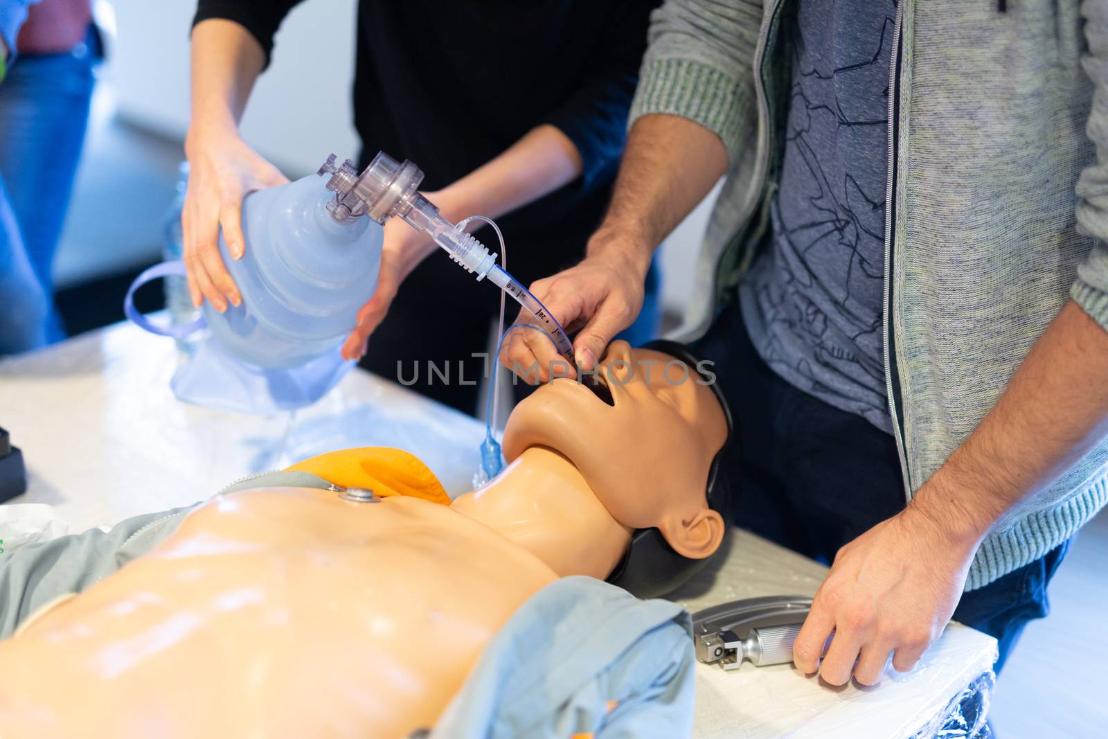 Medical doctor expert instructor displaying method of patient intubation on medical education training and workshop. Participants working in teams learning new medical procedures and techniques.