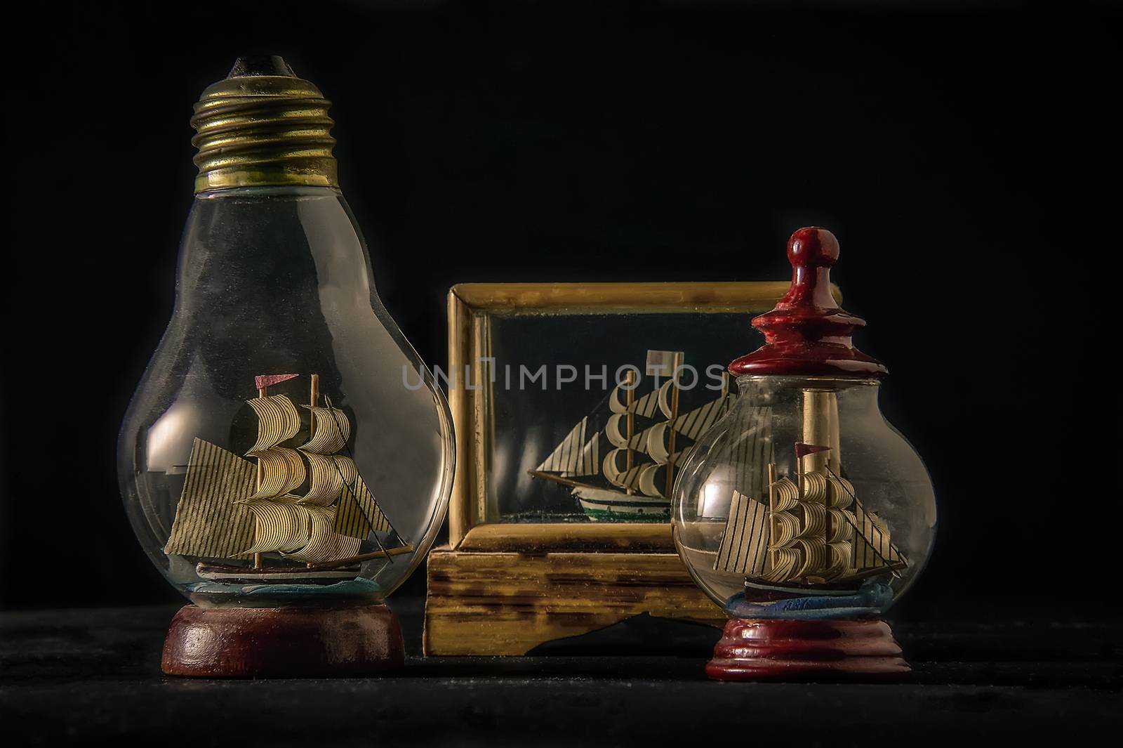 Ships in bottles inside glass cases of various shapes: a still life of vintage decoration items.