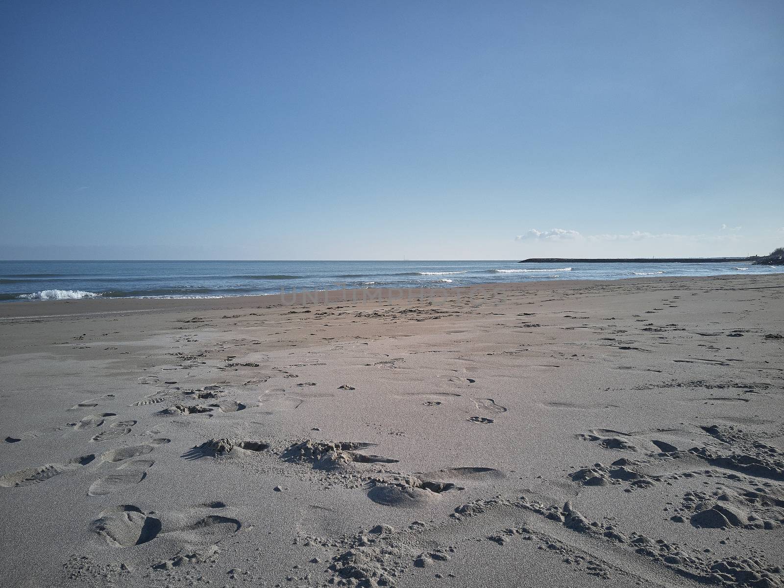 View of a deserted beach with impronet on the sand left by the passage of someone who has ventured to visit this place of peace and tranquility.