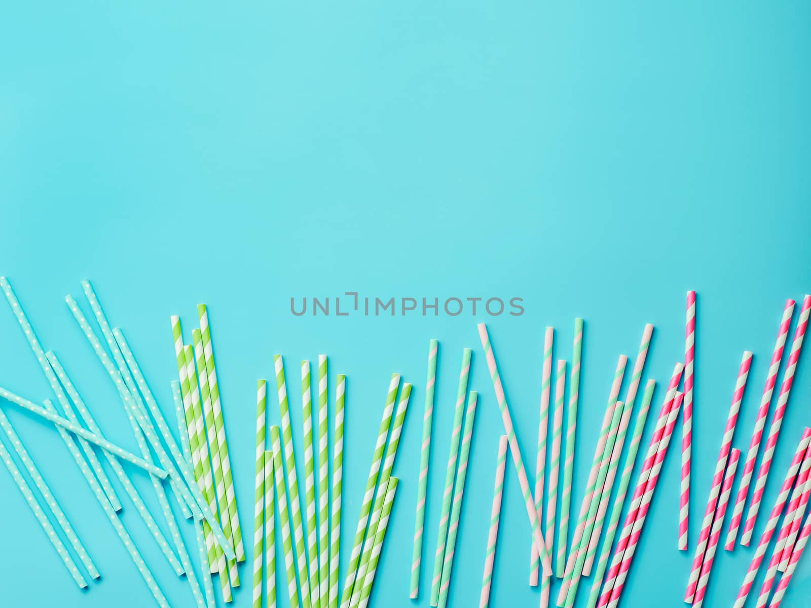 Striped paper straws on pink and blue background by fascinadora