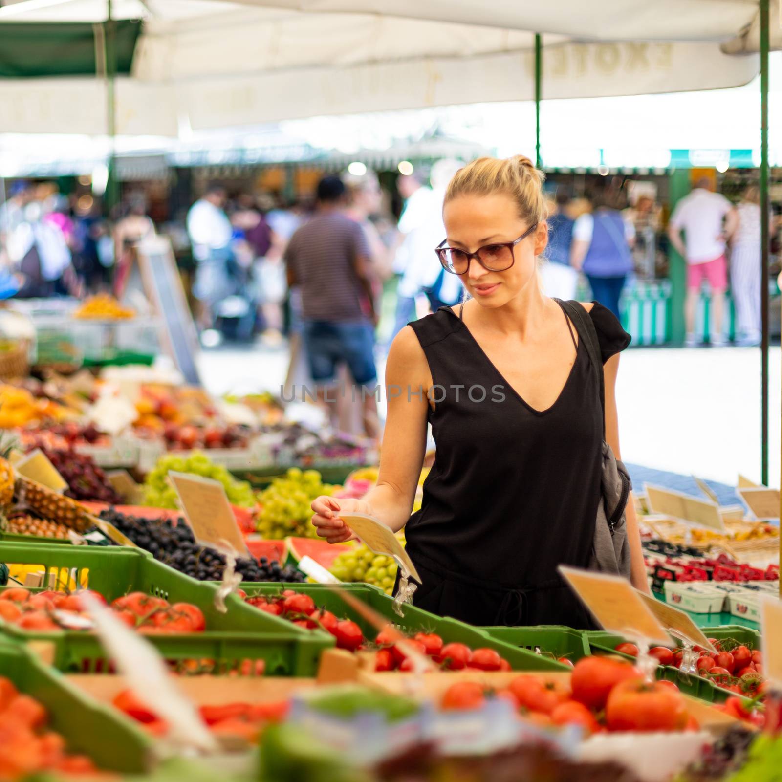 Woman buying fruits and vegetables at local food market. Market stall with variety of organic vegetable.