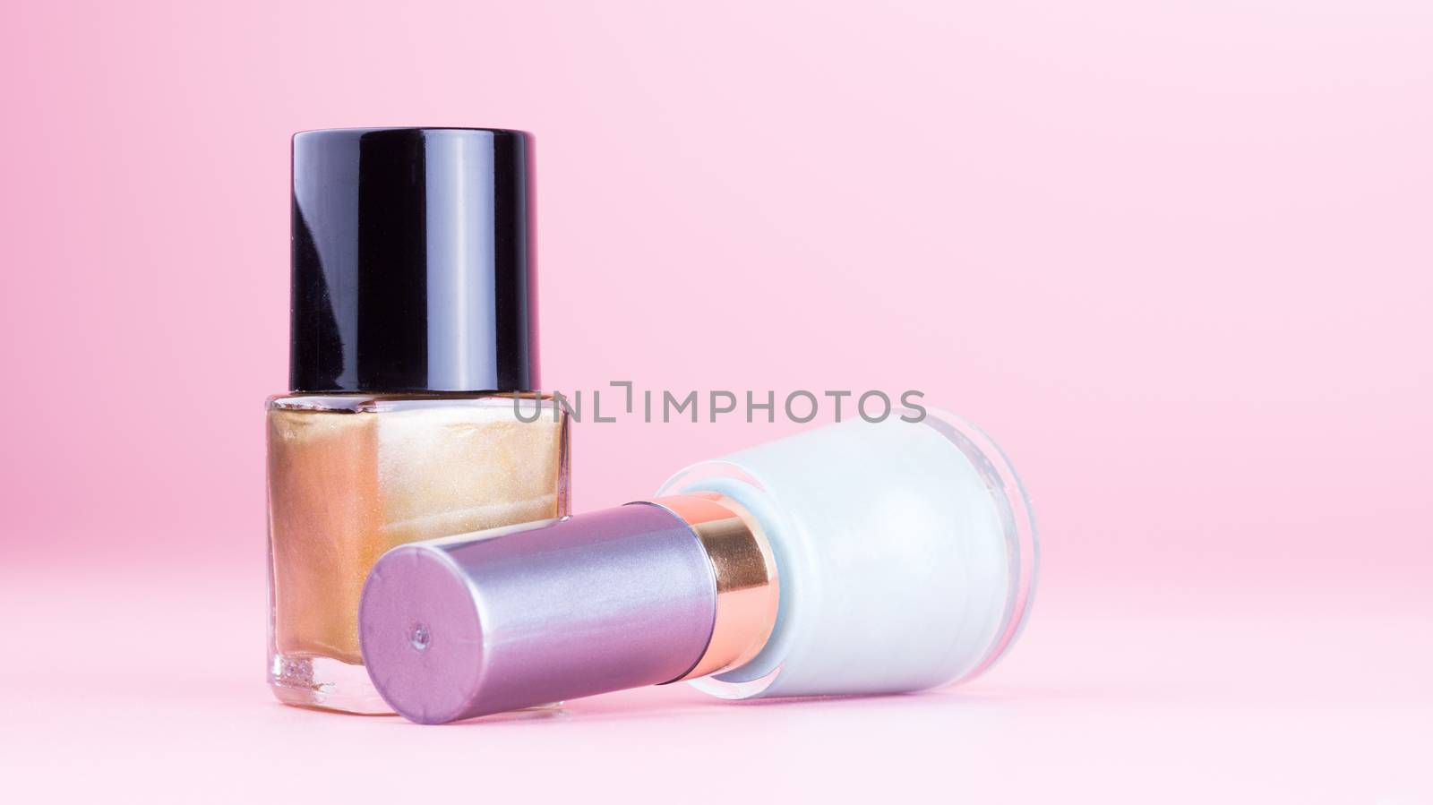 Two bottle of nail polish on pink background
