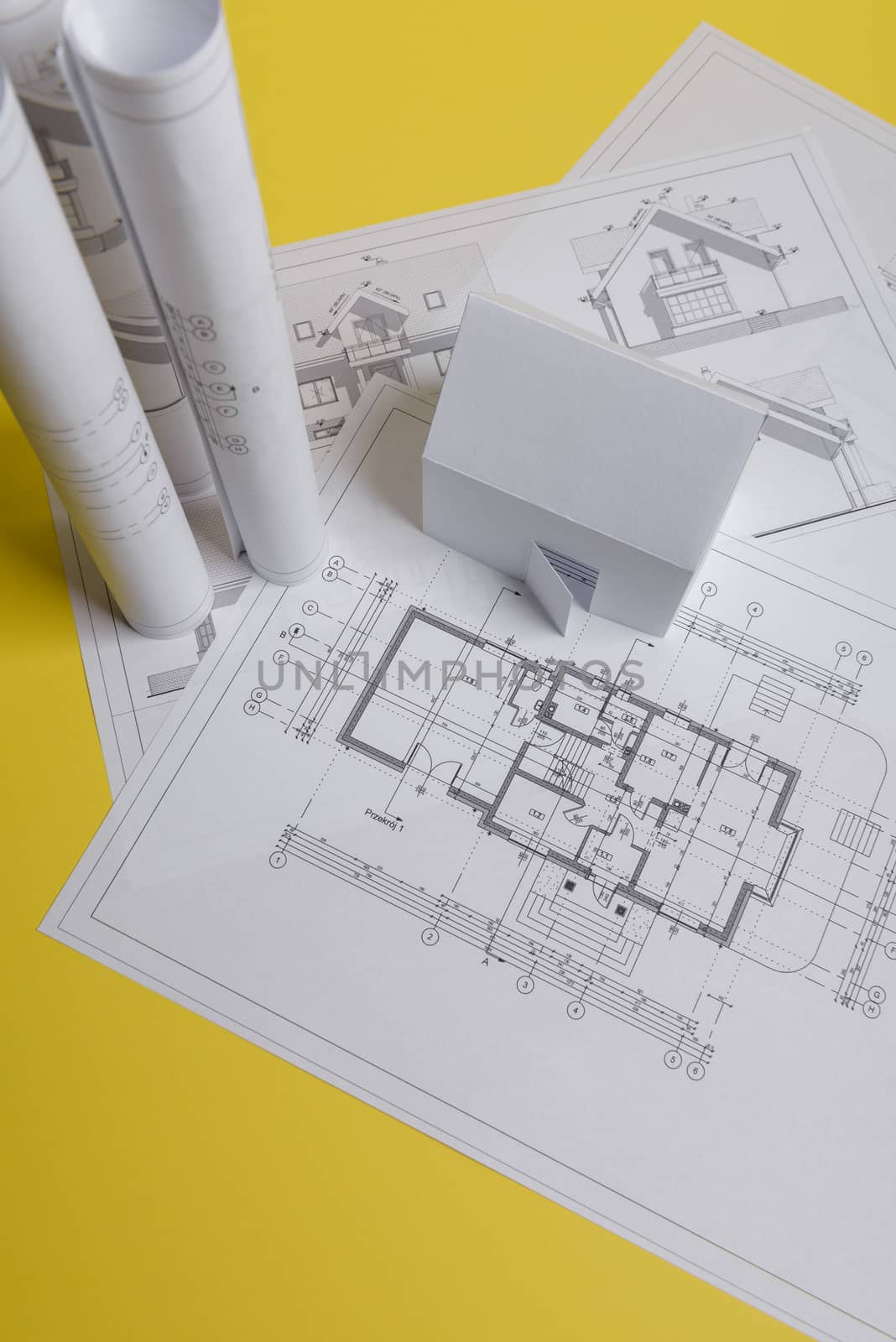 White family paper house, house projects plan and blueprints on yellow background paper. Minimalistic and simple concept, style. Vertical orientation.