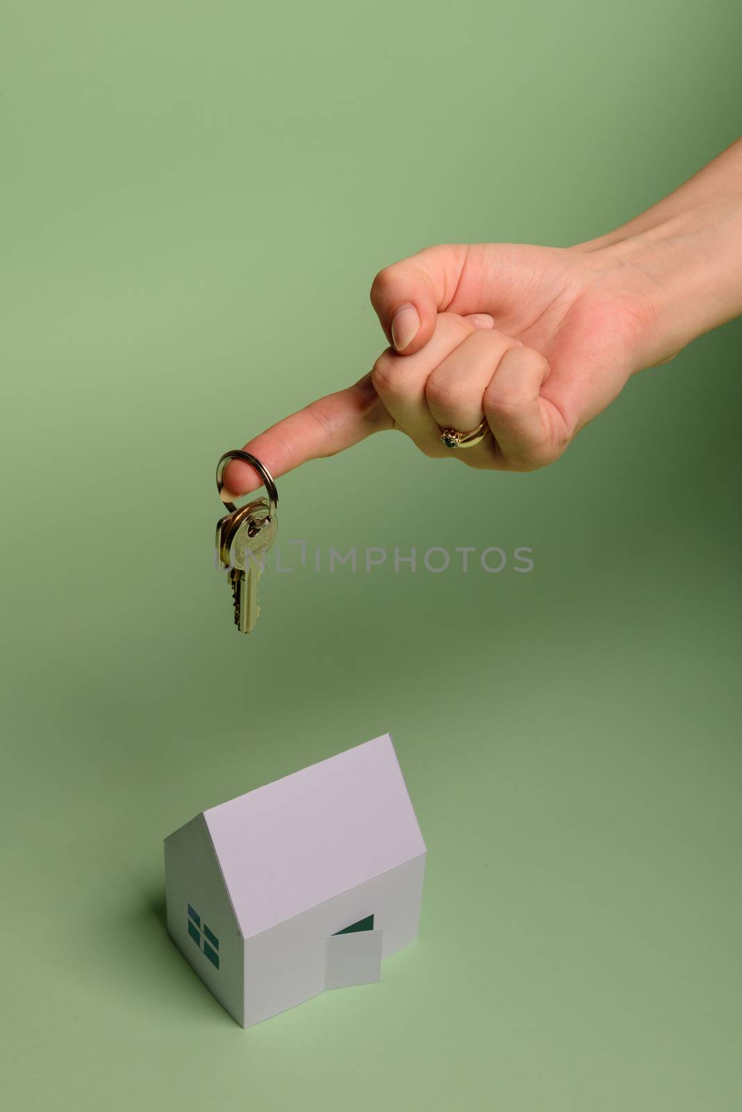 White family paper house. House keys in hand on mint background paper. Minimalistic and simple concept, style. Copy space. Vertical orientation. Family moving or removal concept.