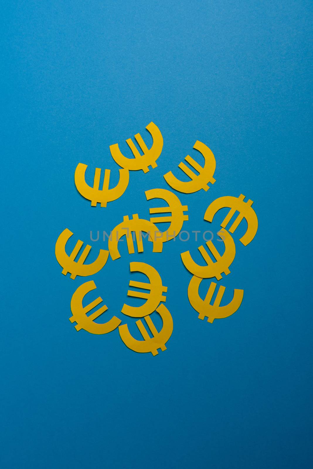 Paper yellow symbols of euro currency on blue background. View from above with copy space
