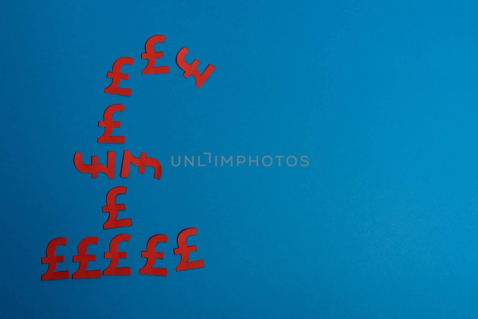 Paper yellow symbols of british pound currency on blue background. View from above with copy space