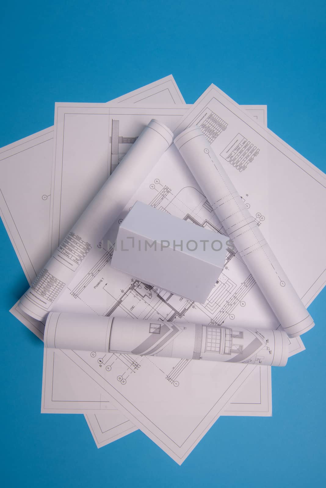 White family paper house over block of flats on blue background paper. Minimalistic and simple concept, style. Copy space. Vertical orientation.