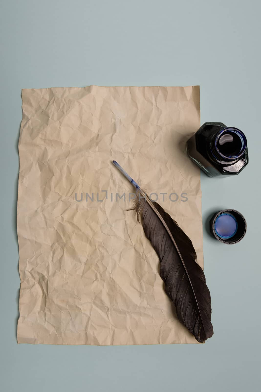 Raven feather, inkwell and old yellowed paper on red background. Copy space. Old letter.