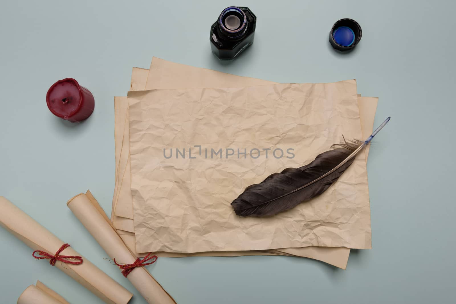 Raven feather, inkwell and old yellowed paper on red background. Copy space. Old letter.