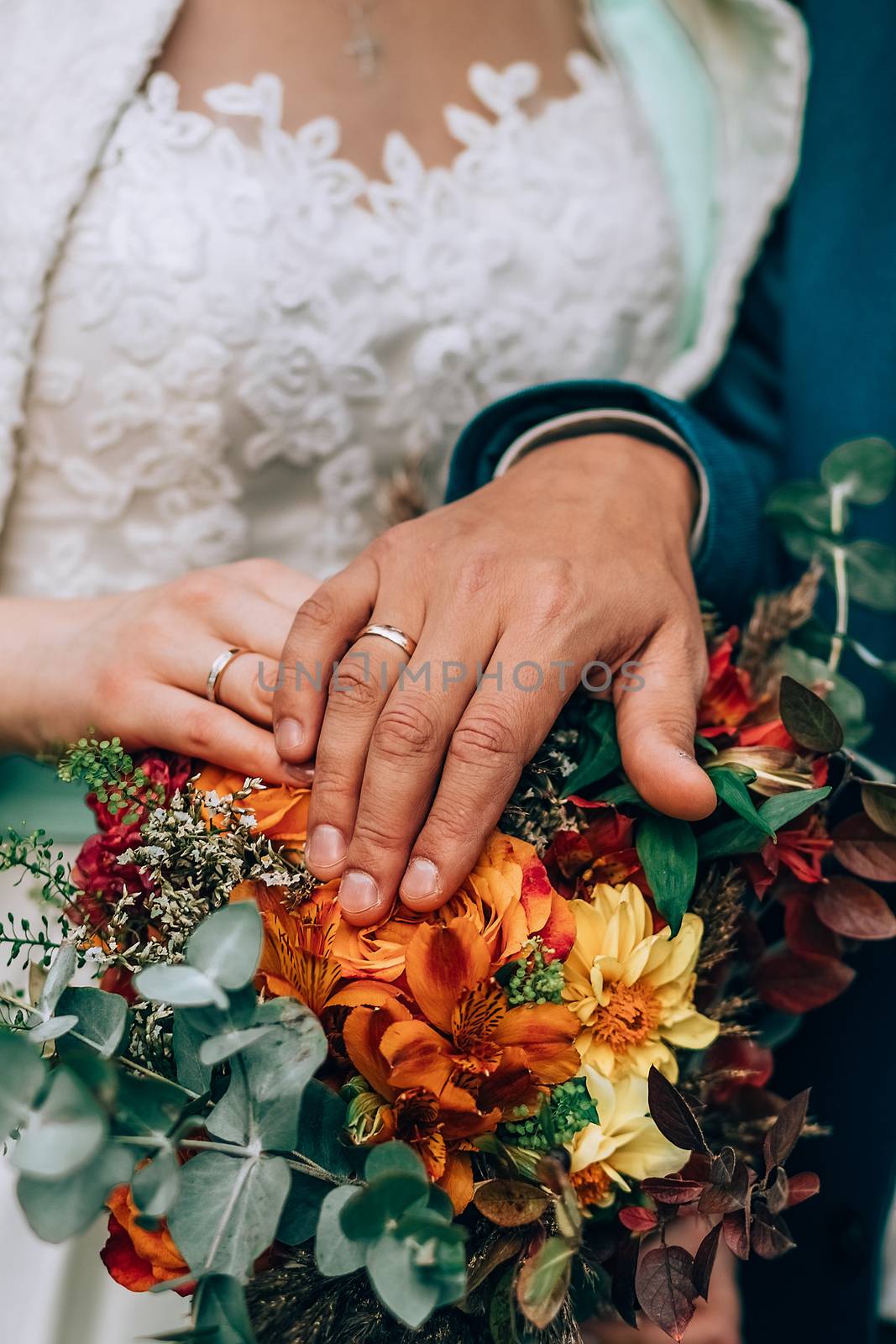 Crop blurred just married couple in elegant clothes hugging and holding beautiful bouquet of fresh colorful flowers in composition with green and brown herbs