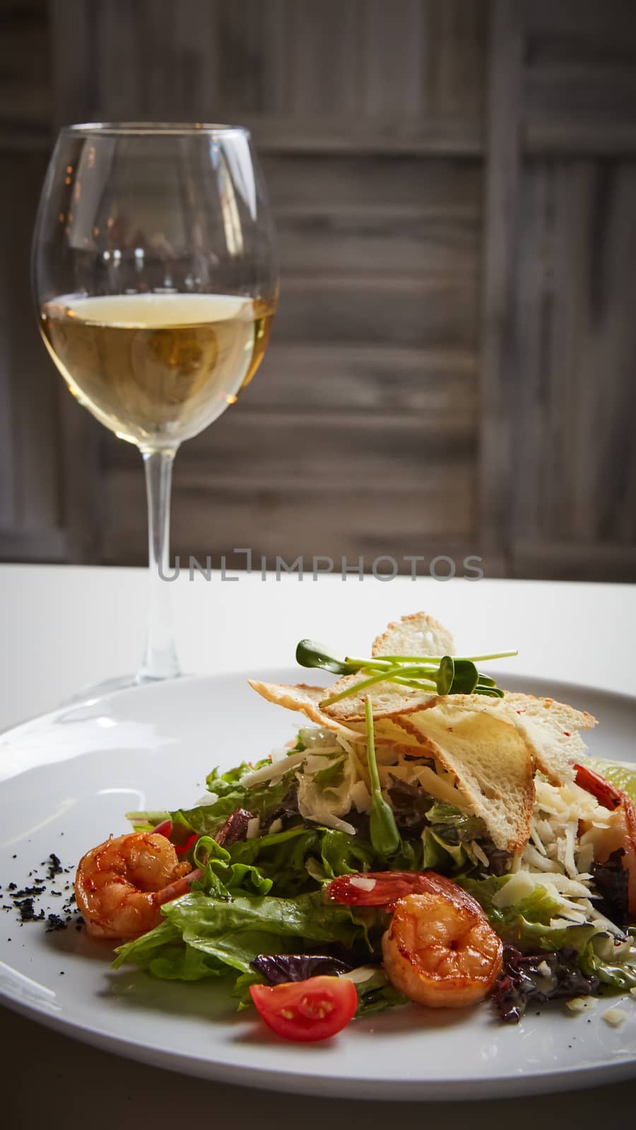 Fresh caesar salad on white bowl with parmesan cheese and shrimp by sarymsakov