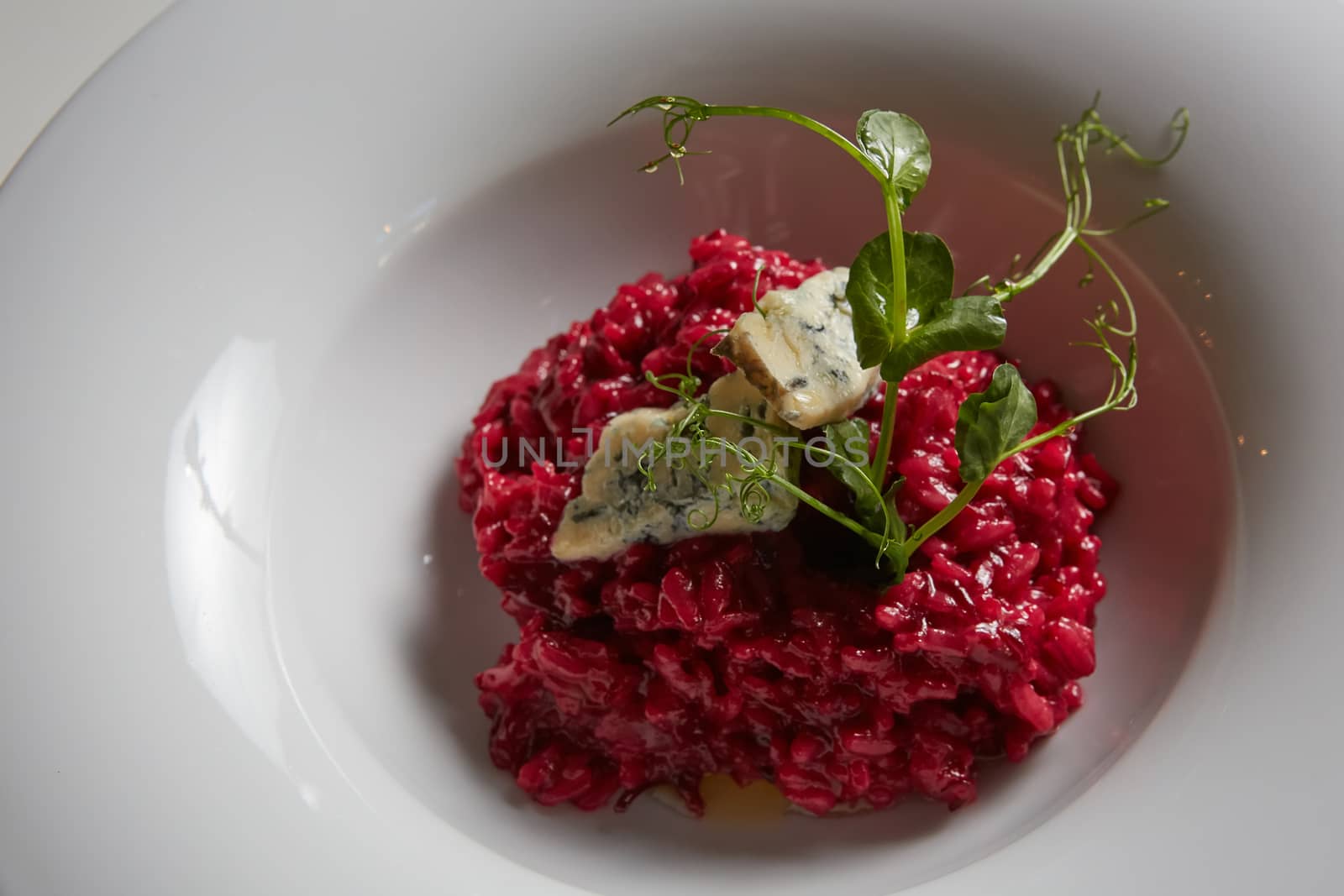 Beetroot risotto with blue cheese on a white plate. by sarymsakov