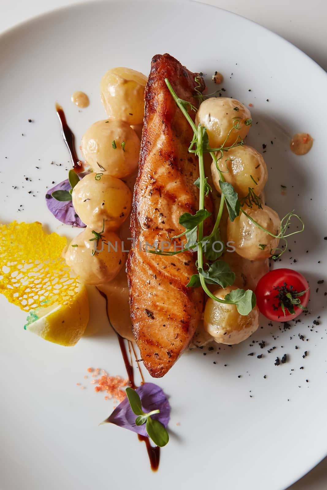 Roast salmon with potatoes on white plate. Shallow dof.