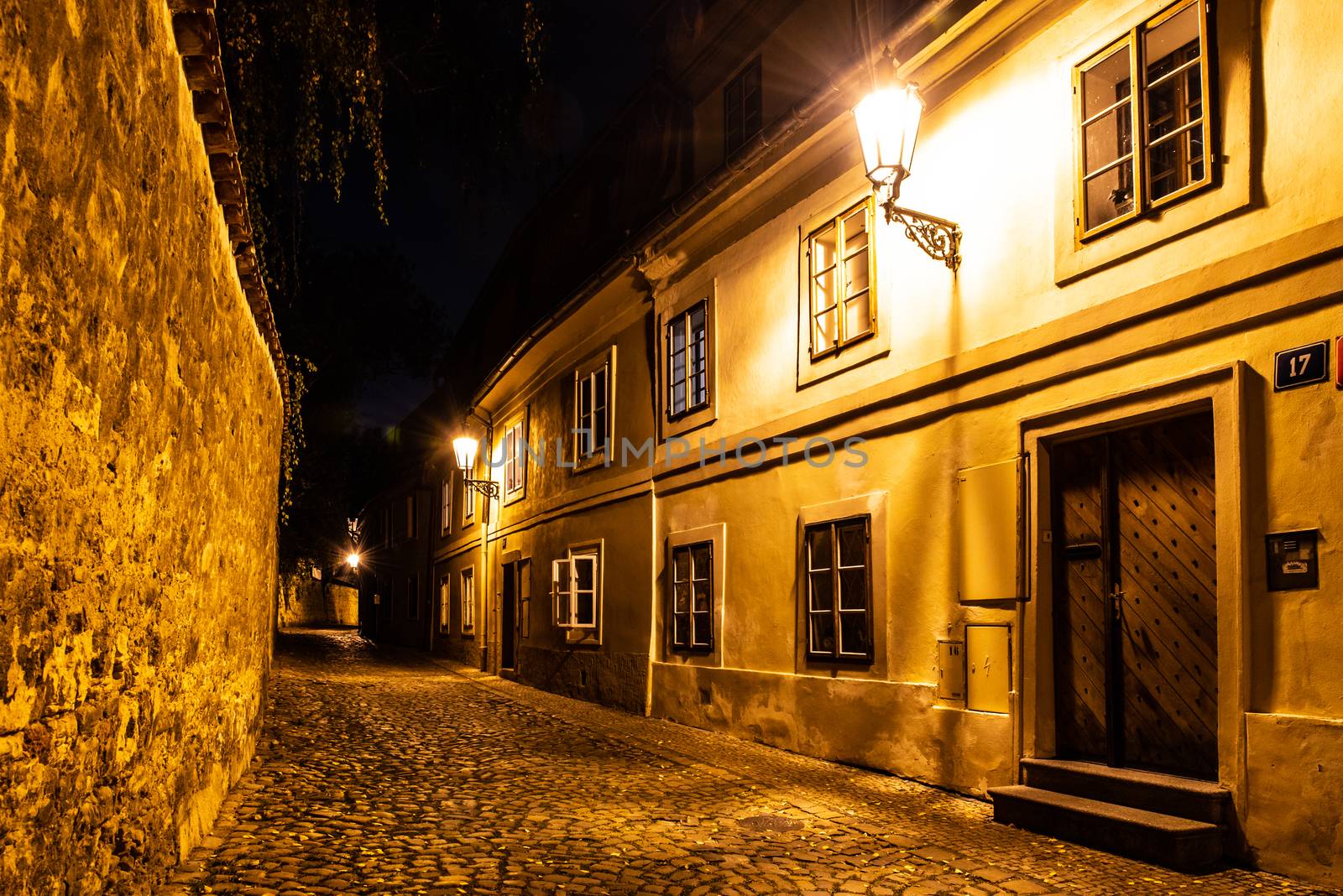 Narrow cobbled street in old medieval town with illuminated houses by vintage street lamps, Novy svet, Prague, Czech Republic. Night shot by pyty