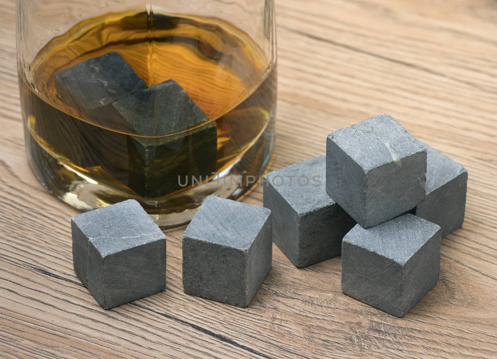 Glass with whiskey and whiskey stones on wooden background