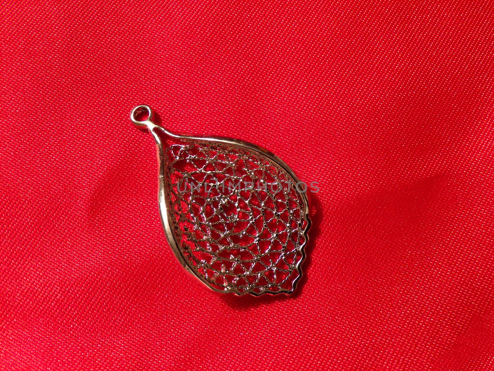 Beautiful pendant on red silk fabric. Pendant made of silver in the form of a tree leaf.