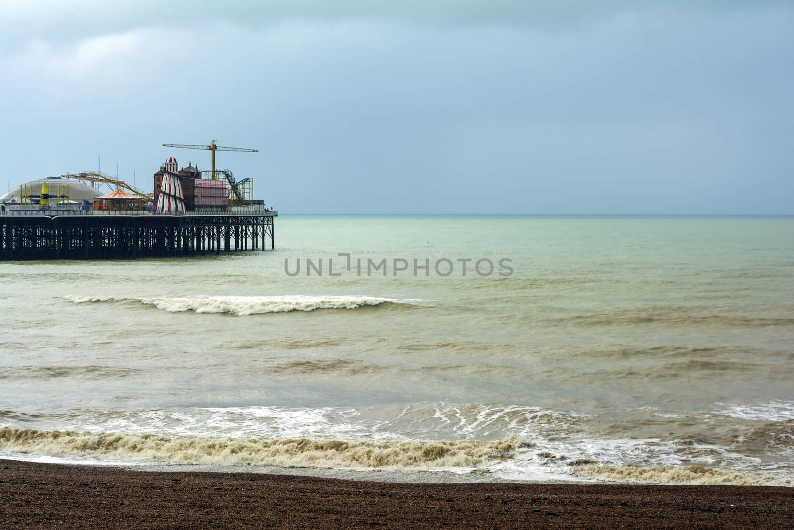 The shingle beach at Brighton, East Sussex, UK in autumn and the Brighton Palace Pier on a cloudy day, in autumn.