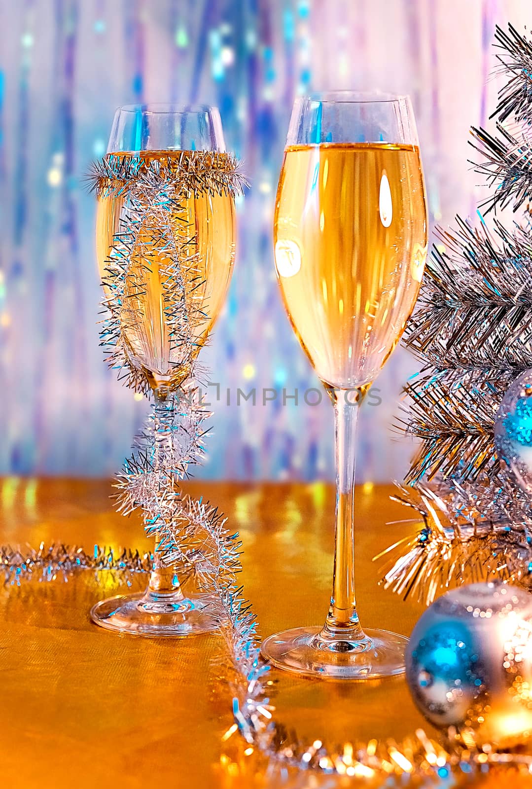 Glasses with wine, tinsel, Christmas tree and toys on the Golden surface