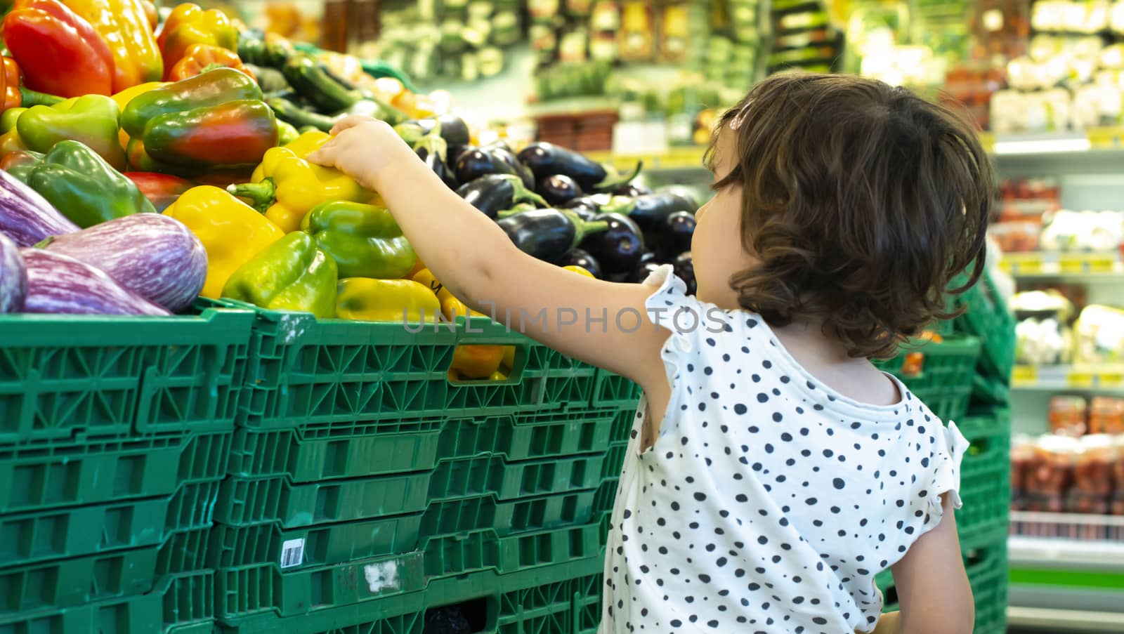 Child shopping peppers in supermarket. Concept for buying fruits by deyan_georgiev