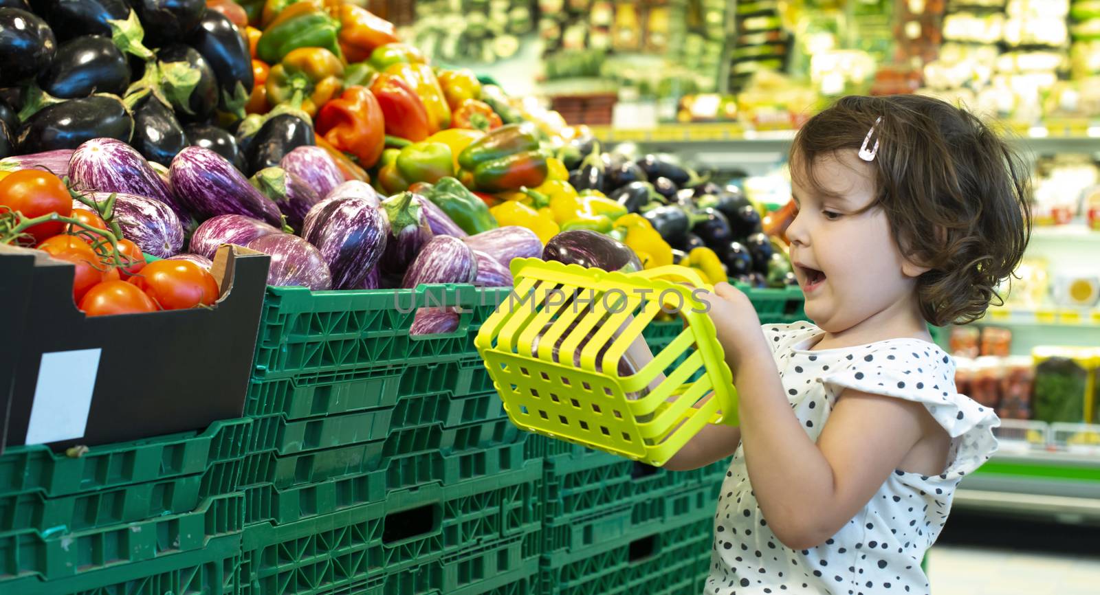 Child shopping eggplants in supermarket. Concept for buying frui by deyan_georgiev