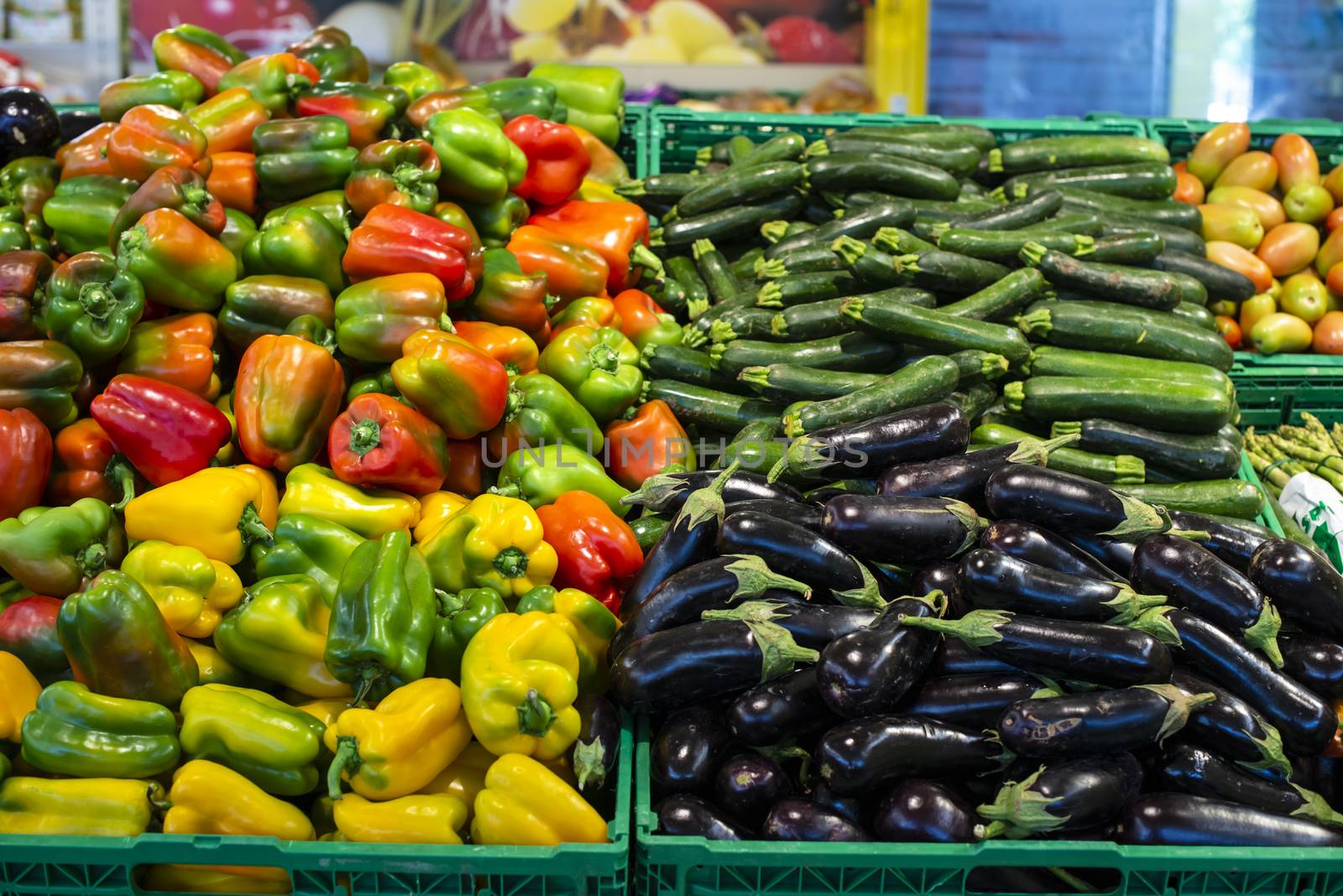 Vegetables in crates in supermarket. Arranged eggplants, peppers and zucchini.