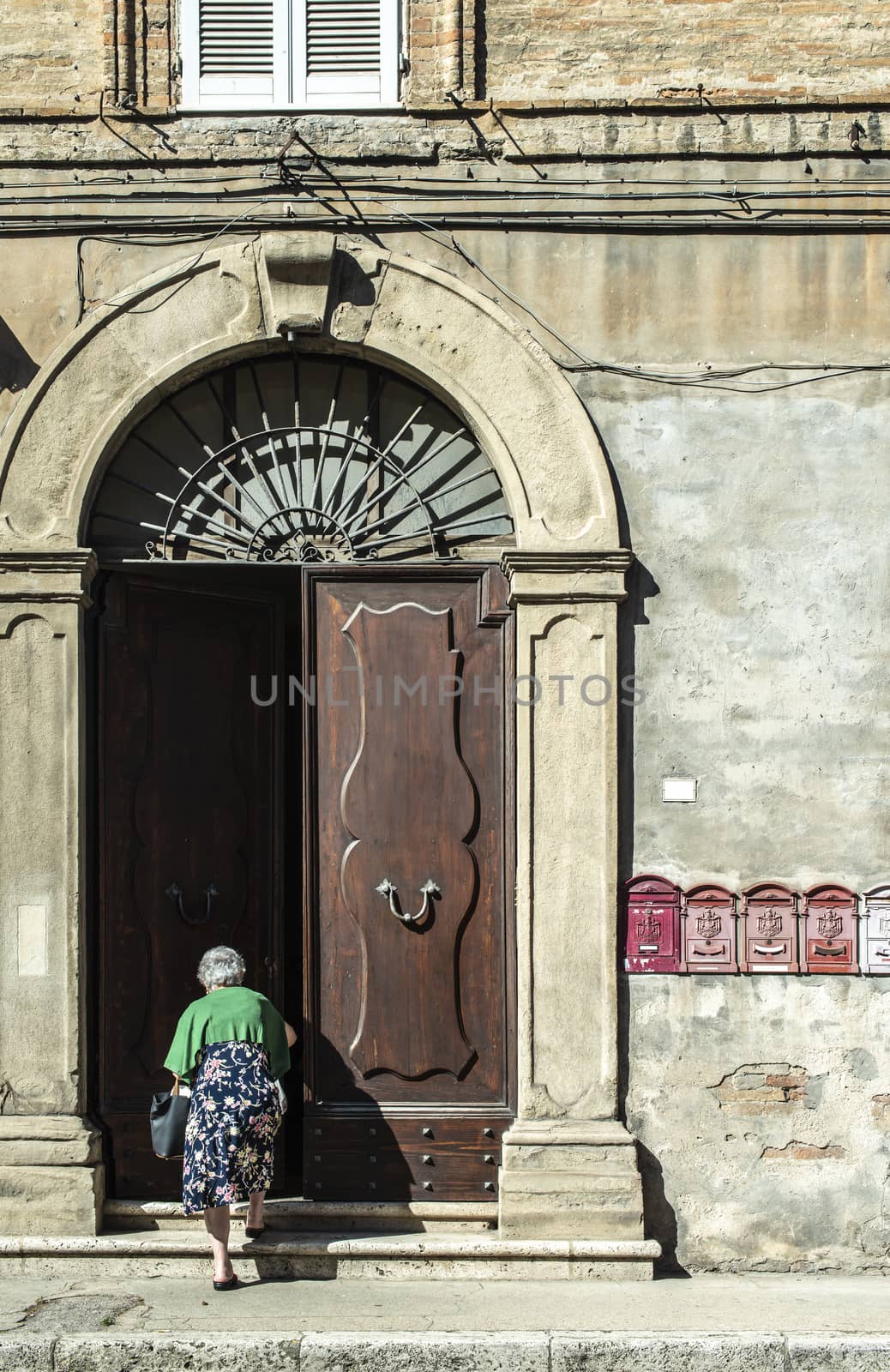 Senior woman enter in the house. Old typical italian wooden door by deyan_georgiev